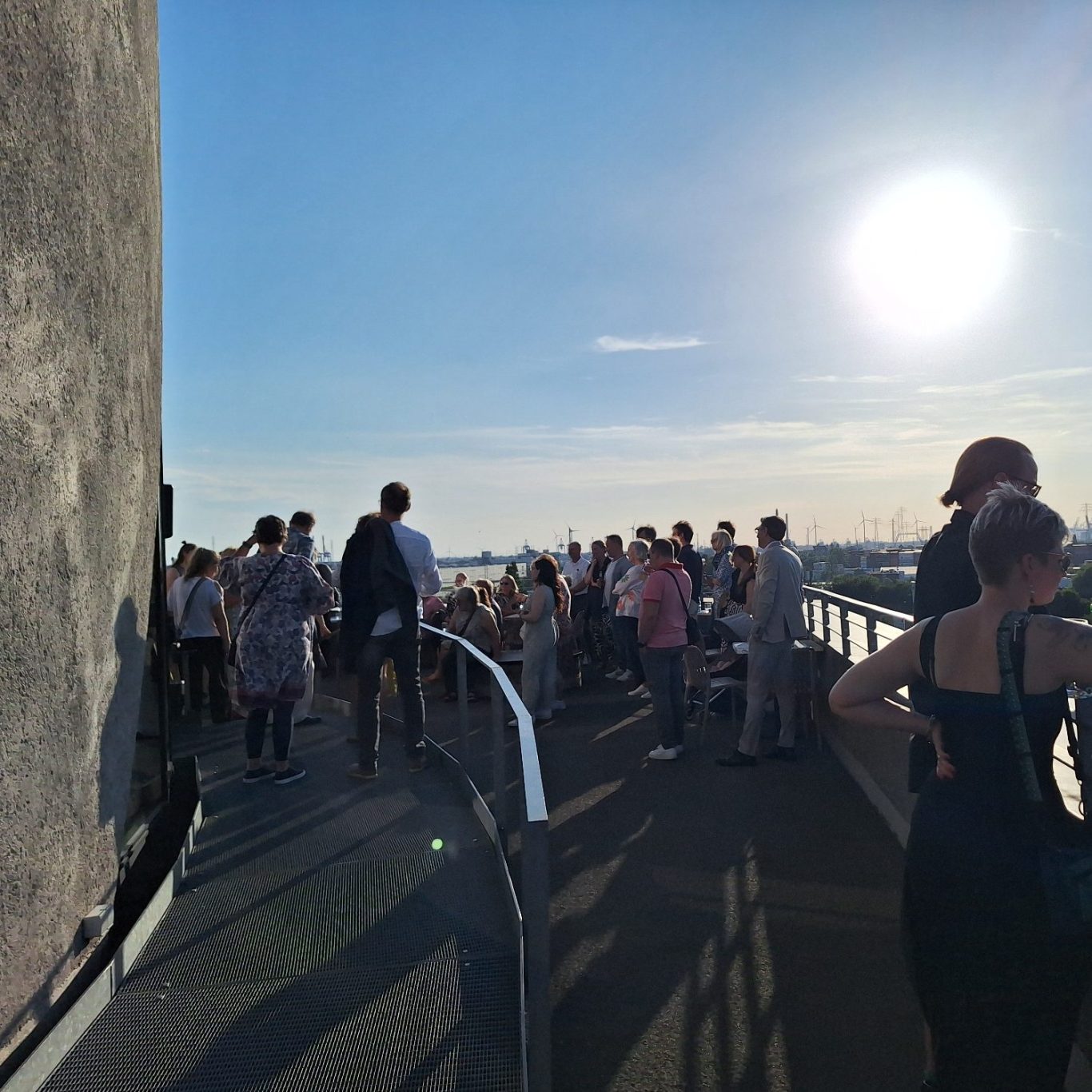 Menschen treffen. Eine Gruppe von Menschen auf einer Veranstaltung im Energiebunker genießen den schönen Ausblick und das tolle Wetter.