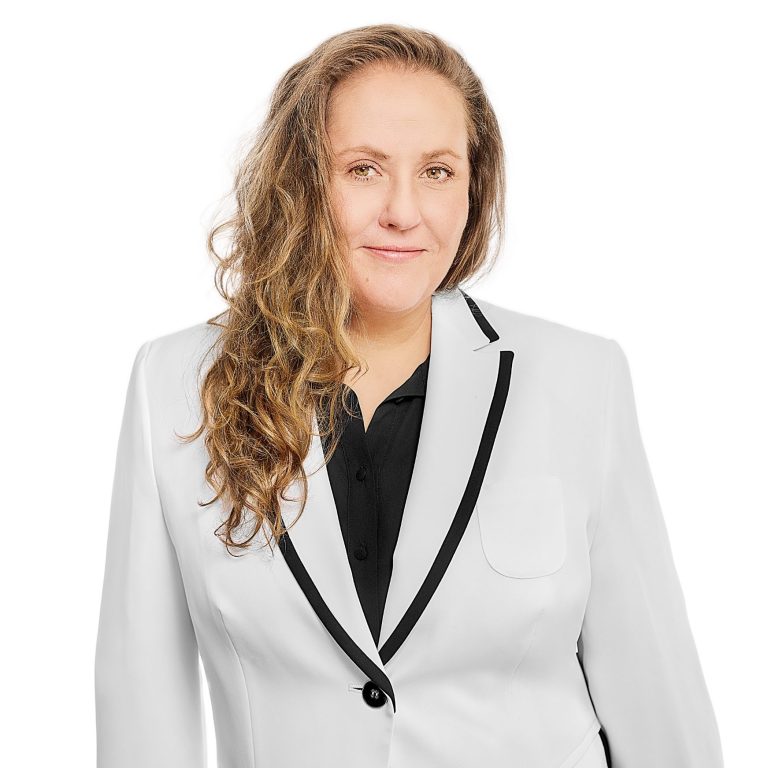 Profilbild von Anne Loeck mit schwarzer Bluse und weißem Blazer, Fotografin: Anja Behrens 