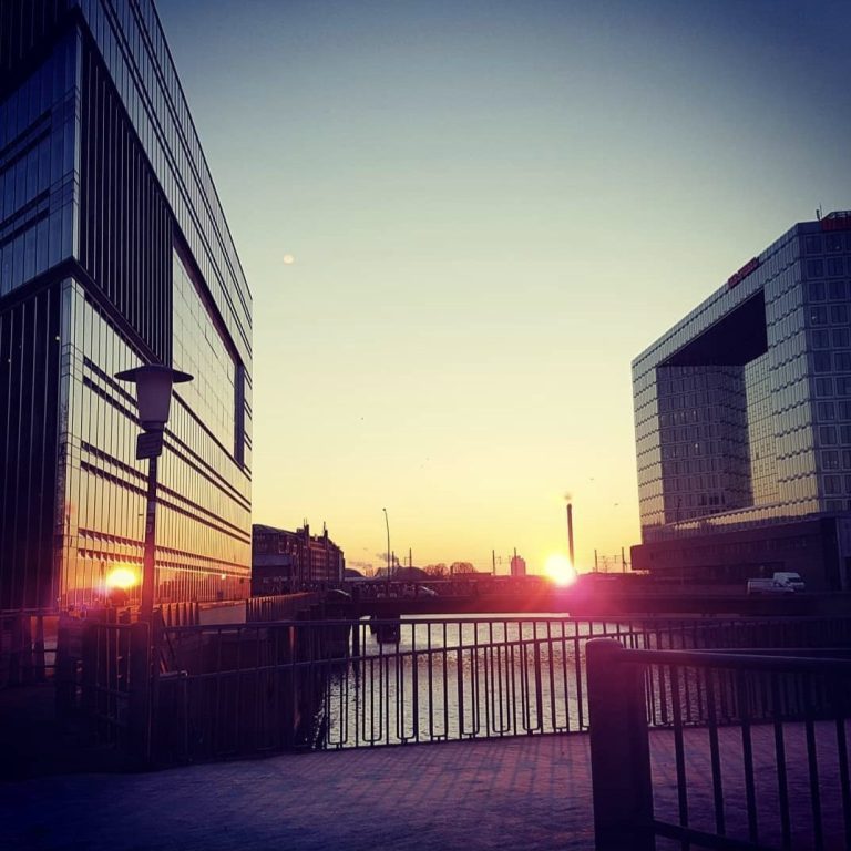 Ein Blick auf einen wunderschönen Sonnenaufgang an der Ericusspitze in der Hafencity, zwischen 2 Häusern durch